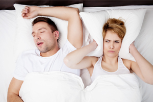 Man Snoring with Wife Covering Her Ears